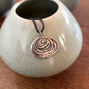 Silver “moon” pendant on leather cord necklace.